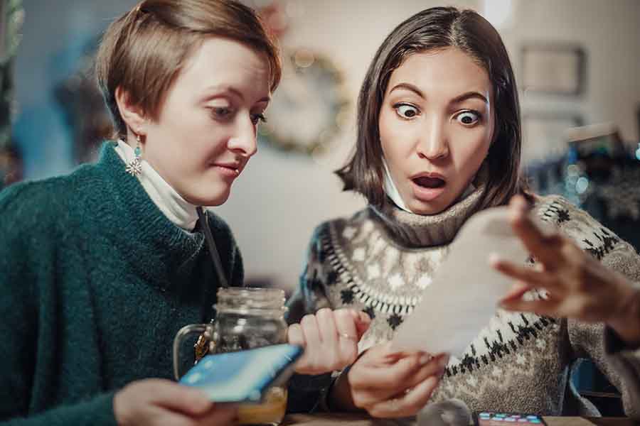 Two women shocked by the amount on the receipt.