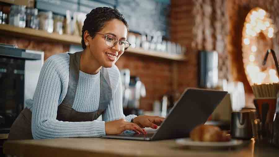 Young restaurant Owner is working on a laptop.