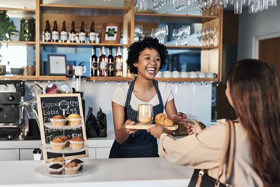 A waitress or employee in small business restaurant helping client at checkout.