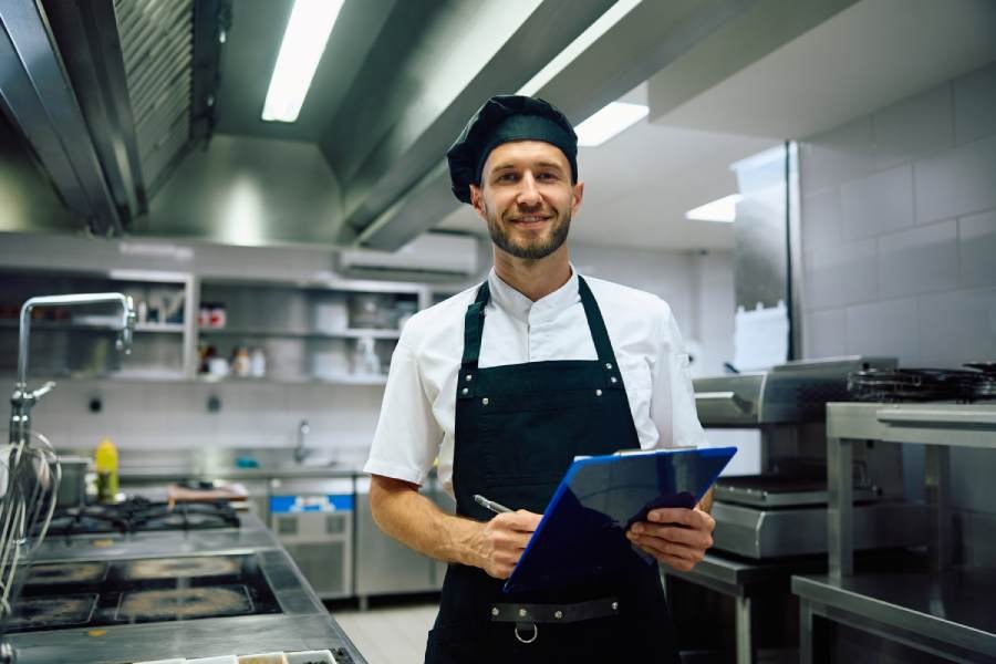 Happy chef filling out paperwork in the kitchen.