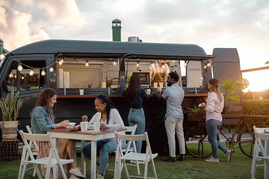 Happy multiracial people having fun eating in a street food truck market.