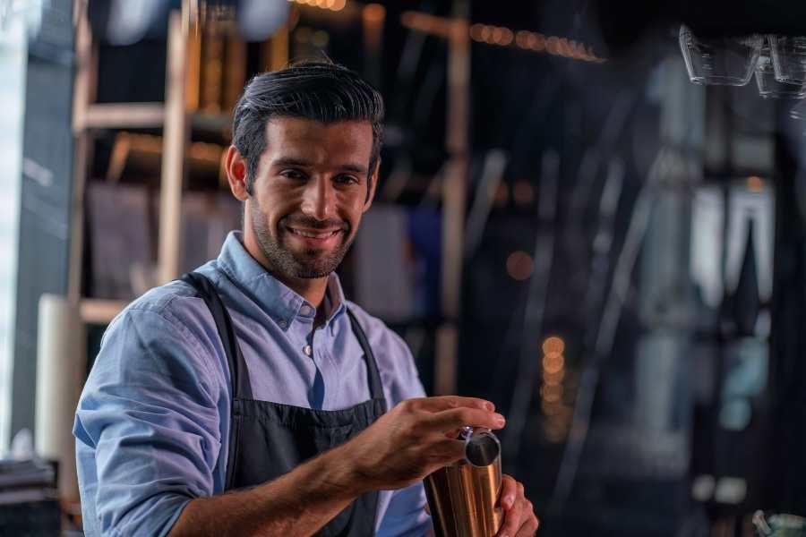 Bartender smile holding in hands a steel shaker.