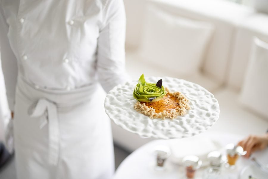 Chef holds a plate with delicious vegetarian meal at restaurant.