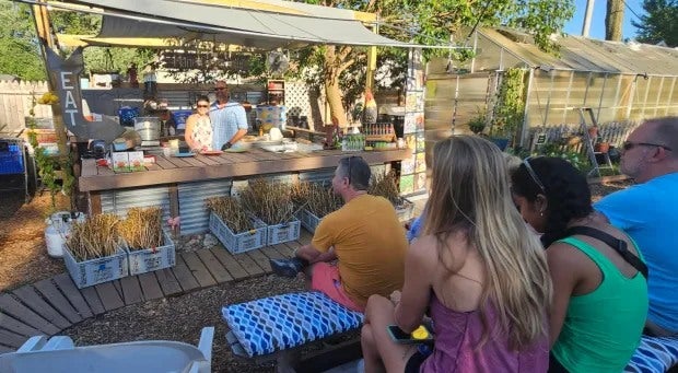 People sitting outside watching a cooking class.