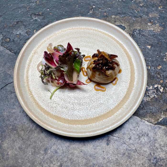 Fancy plate of food with greens and mushrooms.