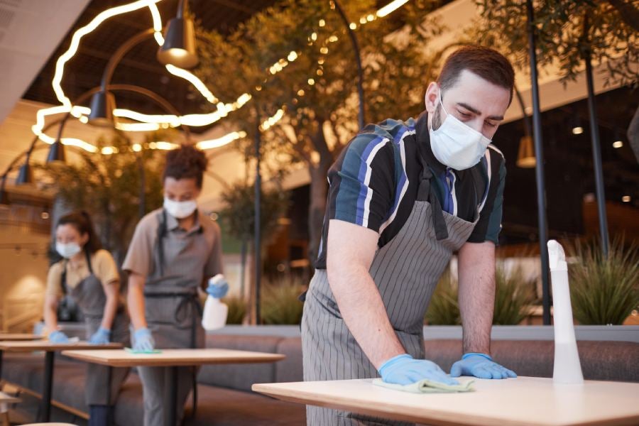 Group of workers sanitizing tables.