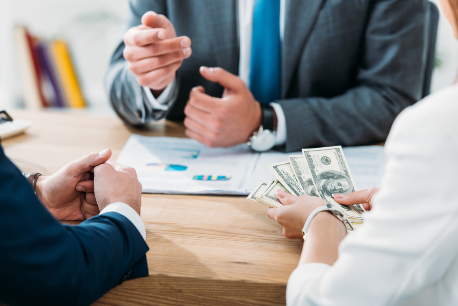 selective focus of investor holding money with colleagues at office