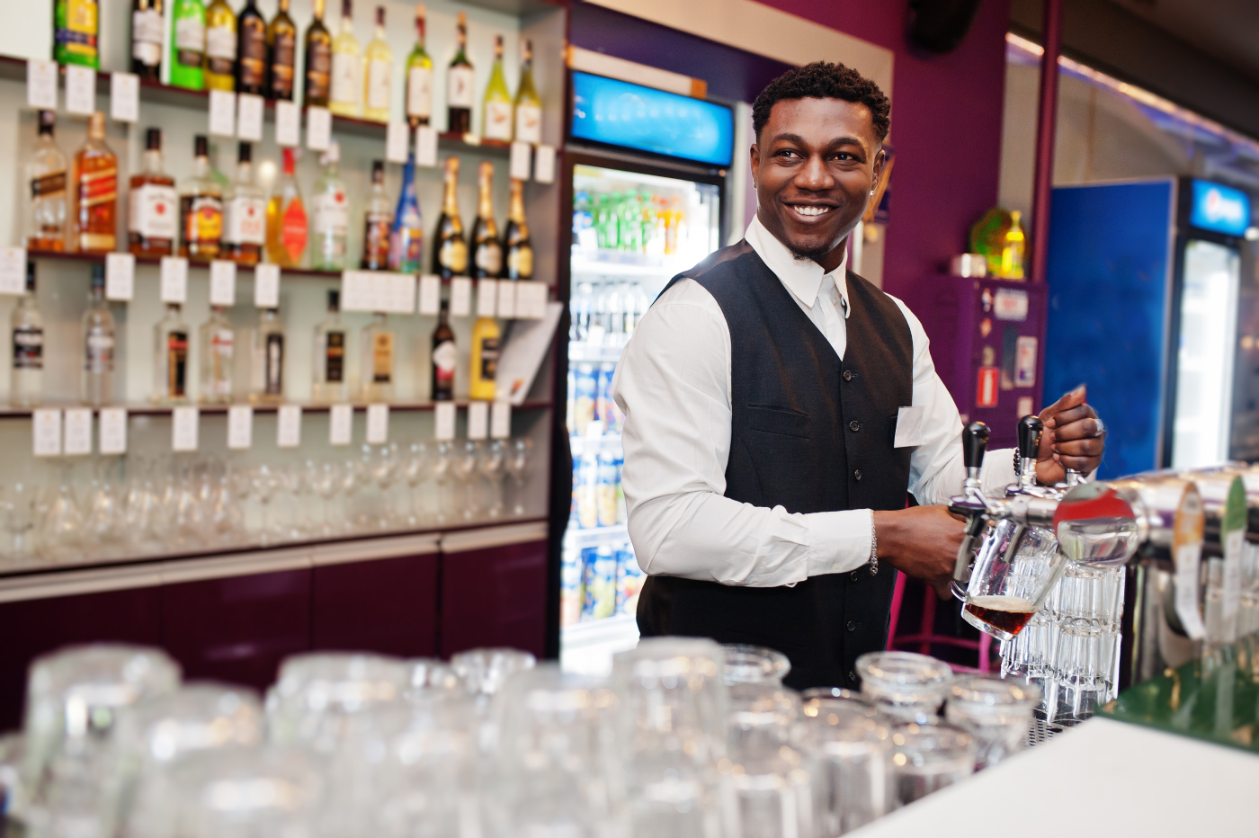 A bartender pouring beer to a mug.