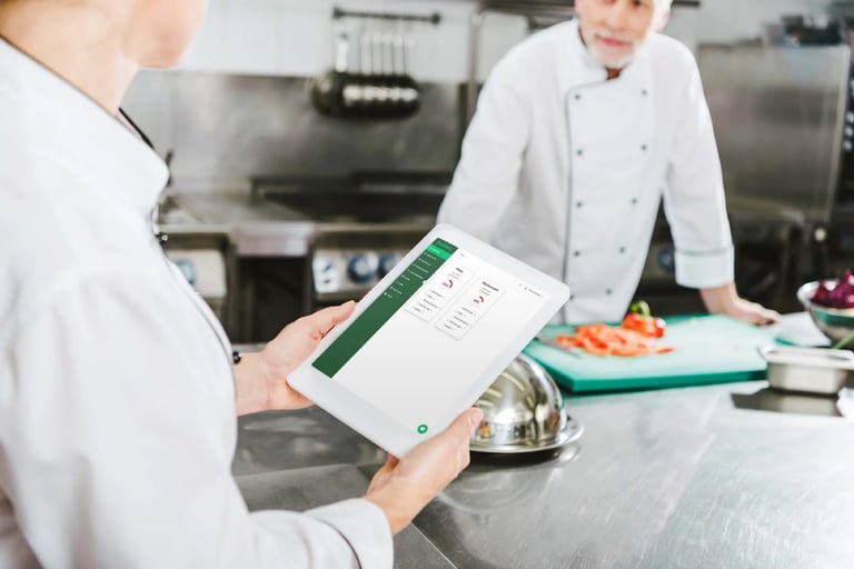 A user is accessing FoodDocs' food safety software in a live kitchen setting.